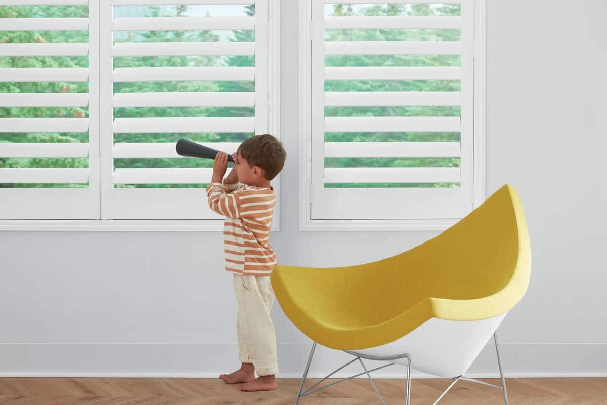 A child with a telescope looks at Hunter Douglas NewStyle® Composite Shutters near Denver, Colorado (CO)