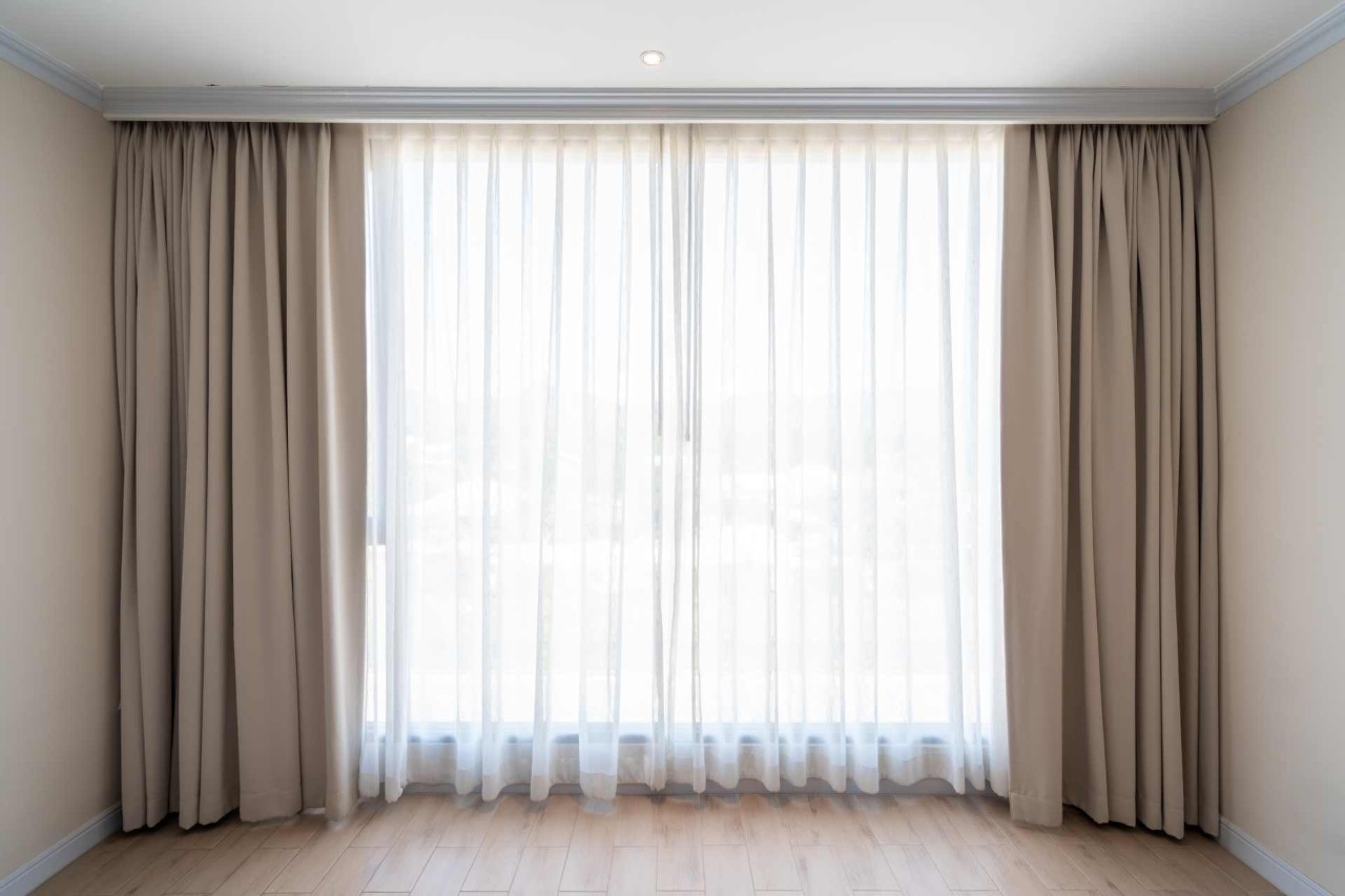 Hunter Douglas Design Studio™ Custom Drapes installed on a window across from a busy street