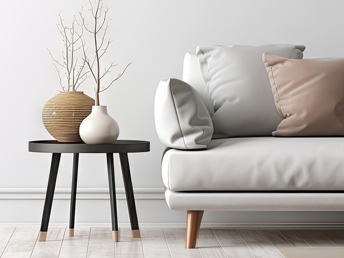 Gray leather sofa with accent pillows next to an end table with vases and plants.